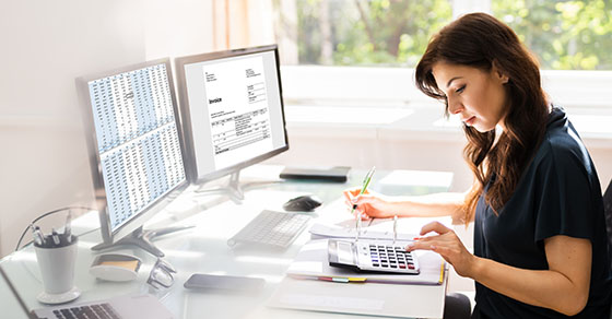 Woman sitting at desk calculating and writing.